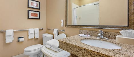 Ein Badezimmer mit Waschbecken, zwei Toiletten, einem Handtuchhalter und gerahmten Bildern an der Wand.