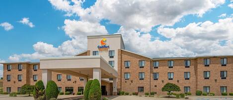 A Comfort Suites hotel with a brick facade, multiple windows, and a covered entrance area.