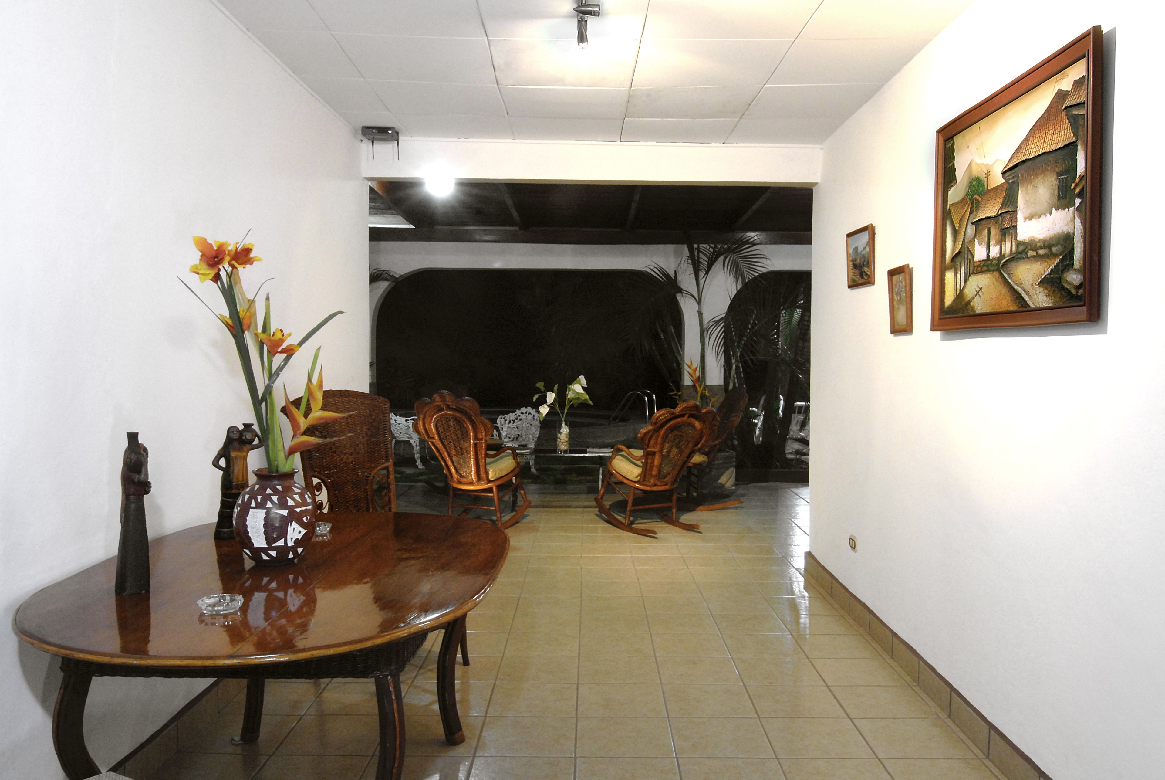 A dining area with a wooden table and chairs, a vase with flowers, and a painting on the wall.