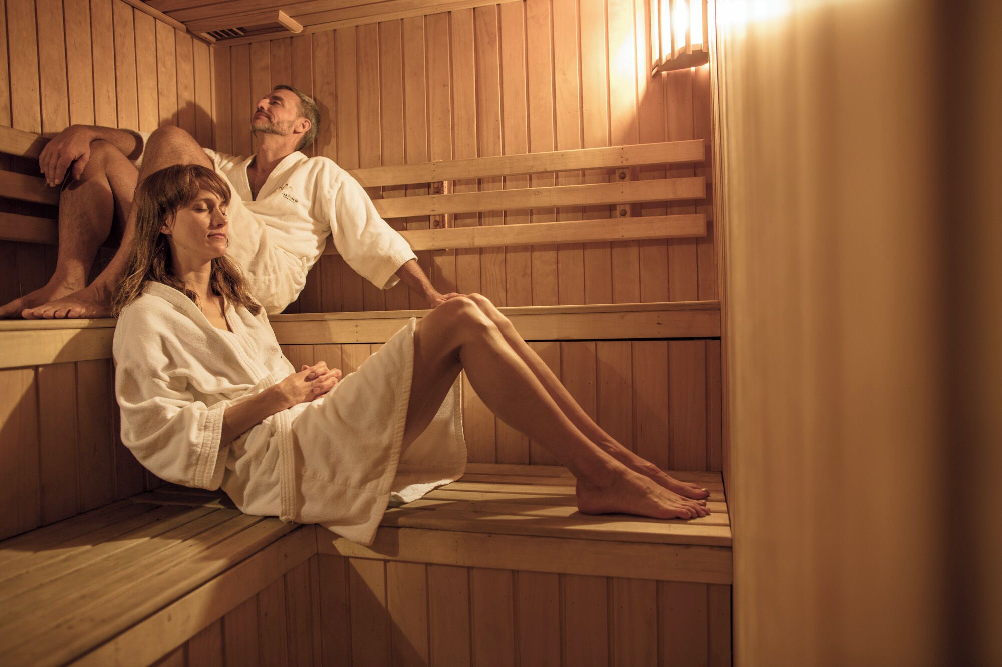 A sauna with wooden benches and benches, where people are sitting and relaxing.