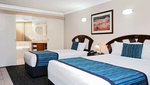 Una habitación de hotel con dos camas, un baño y un cuadro en la pared.