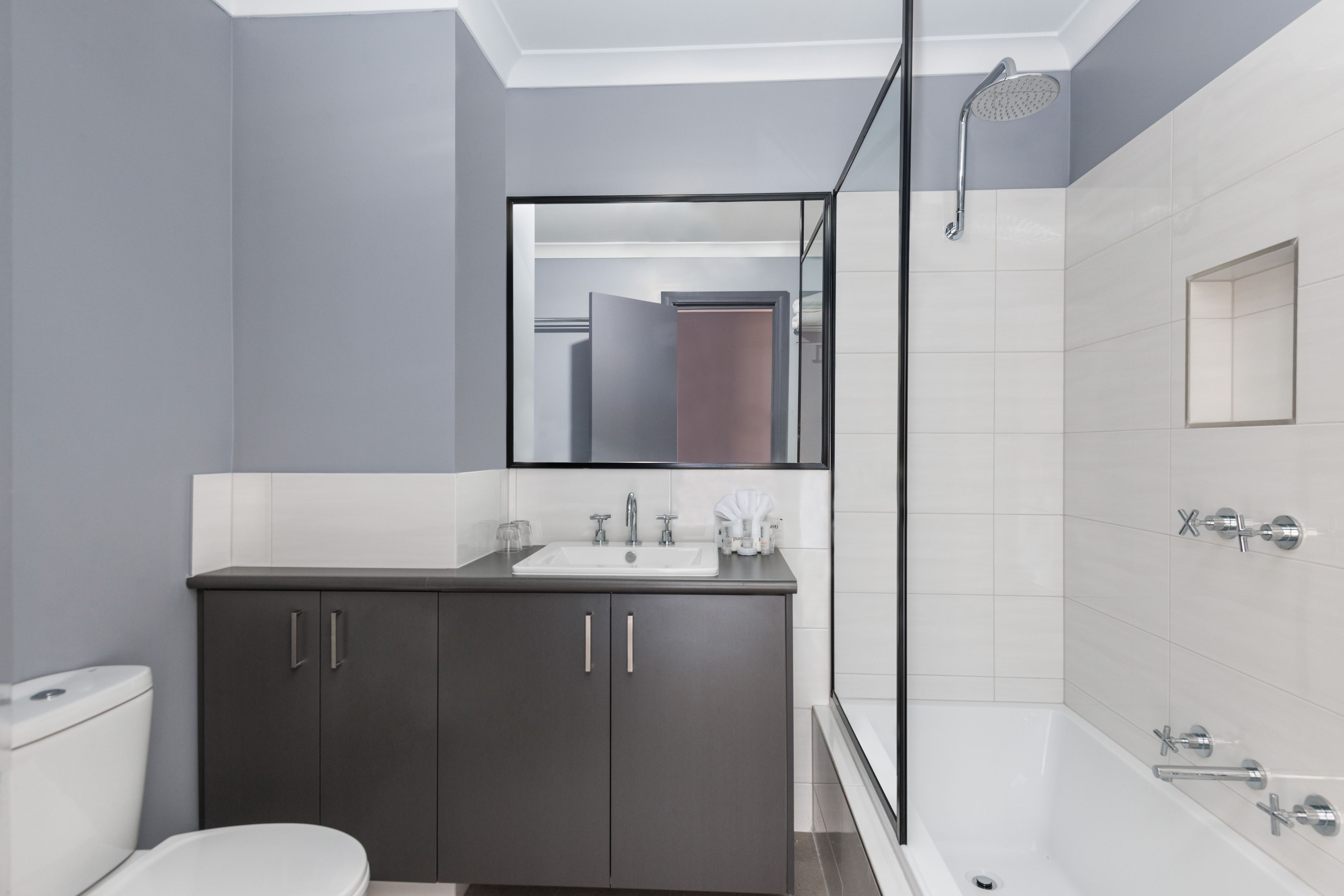 A modern bathroom with a dark vanity, a white sink, and a glass shower enclosure.