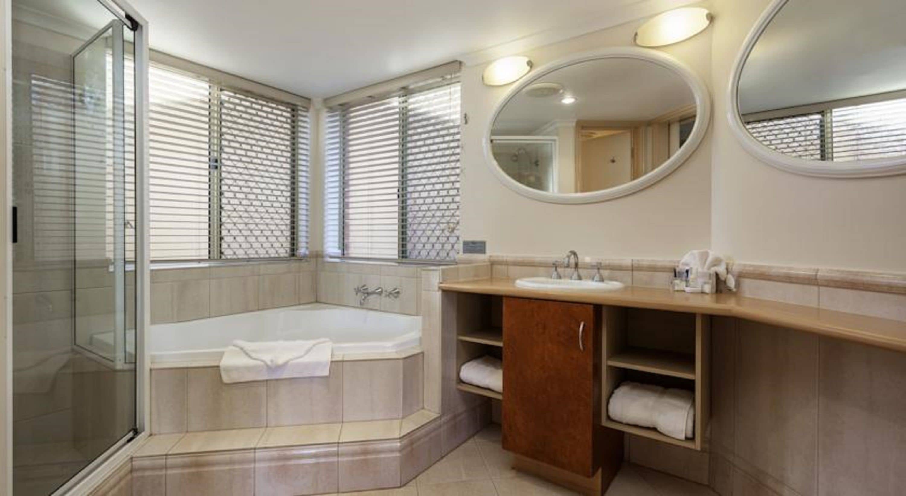 Un baño moderno con ducha de vidrio, bañera independiente y tocador con espejo.