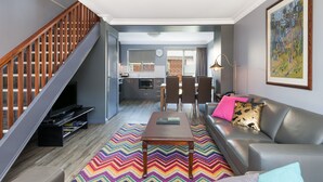 Una sala de estar moderna con escalera, comedor y cocina.