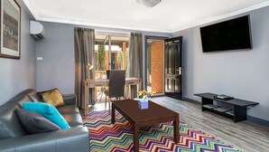 Una sala de estar moderna con un sofá, una mesa de centro, un televisor y una estantería.
