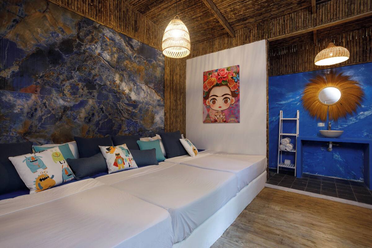 A room with a large bed, a mural, a sink, and a wooden ceiling.