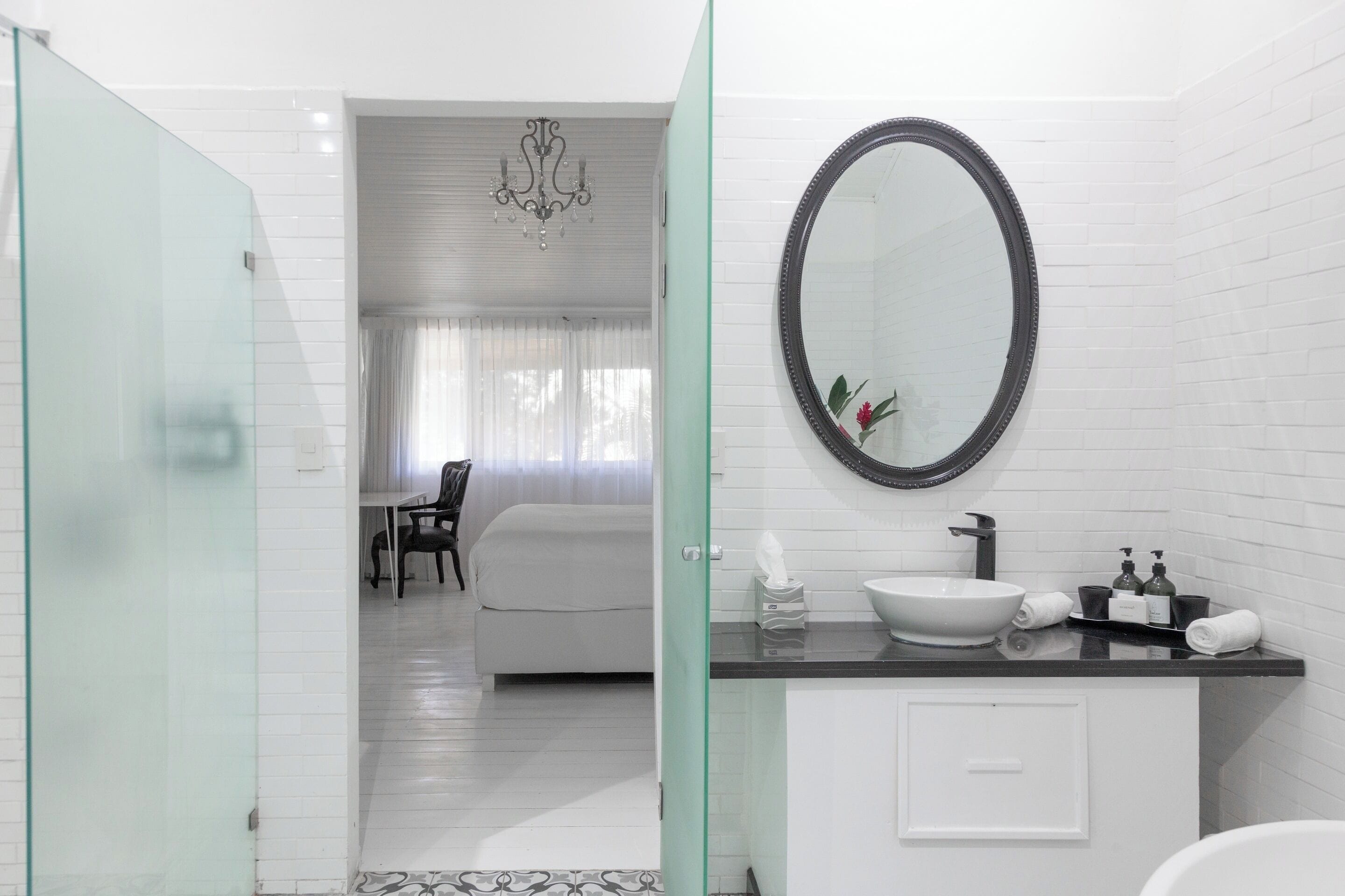A modern bathroom with a glass shower enclosure, a white sink with a black countertop, and a large mirror.