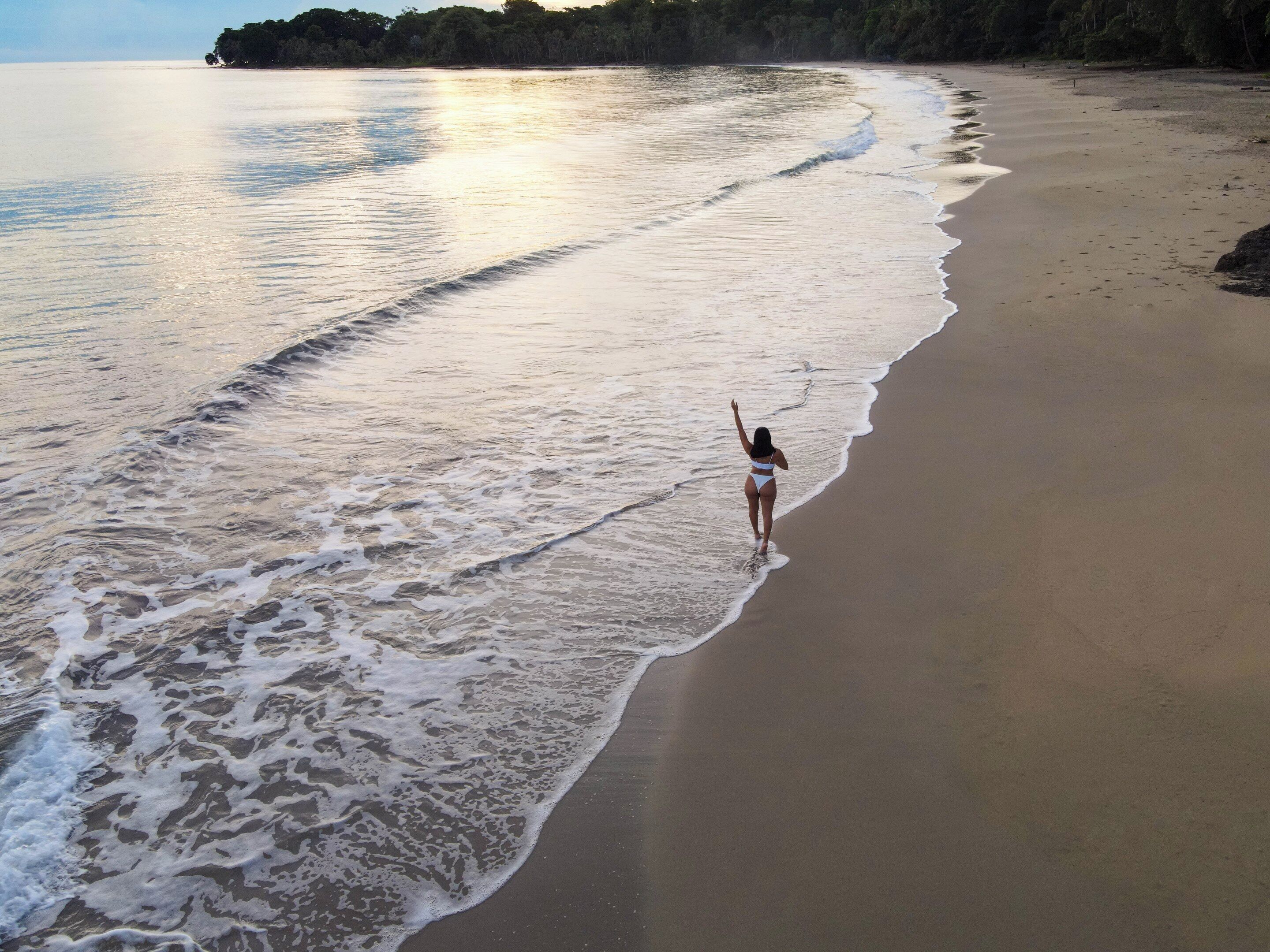 A beach with a person standing in the water.
