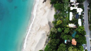 An aerial view of a beachside property with a road, beach, and dense greenery. - Le Cameleon Puerto Viejo (Cahuita)