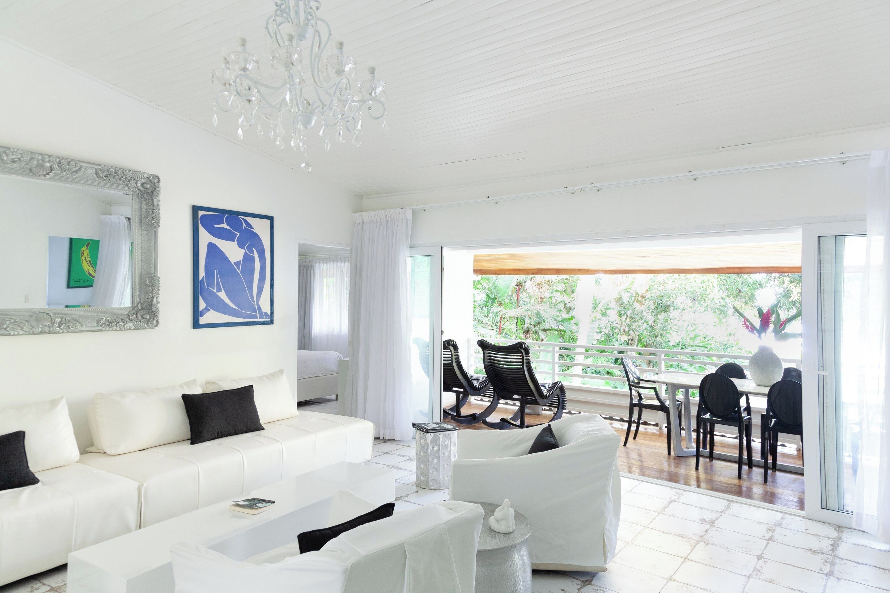 Amplia sala de estar con un sofá blanco, una mesa de centro y un comedor con sillas y una mesa.