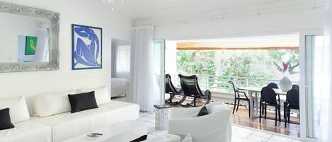 Amplia sala de estar con un sofá blanco, una mesa de centro y un comedor con sillas y una mesa.