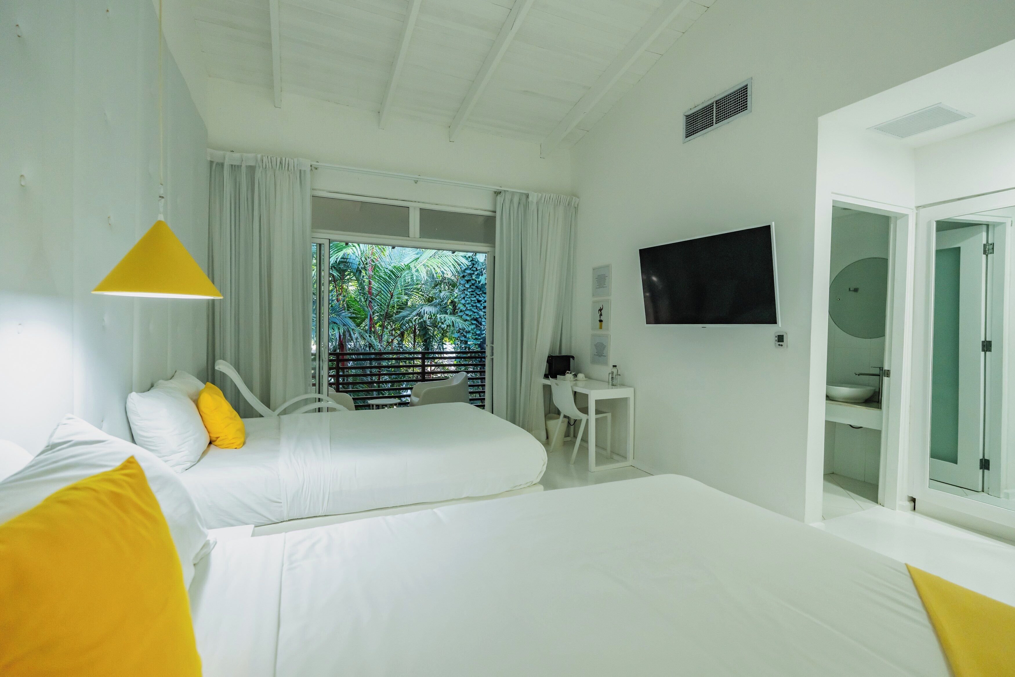Habitación de hotel con dos camas, un escritorio, un televisor y un baño.