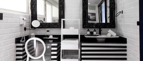 Un baño moderno con paredes de azulejos blancos y negros, dos espejos grandes, un lavabo blanco y un tocador a rayas negras y blancas.