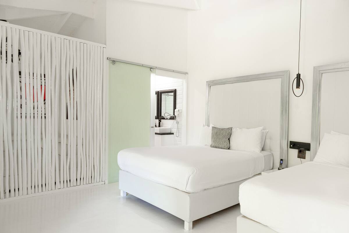 A modern hotel room with two beds, a large mirror, and a wardrobe.