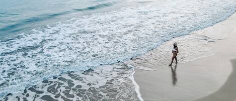 Une plage avec des vagues et une personne qui marche sur le sable.