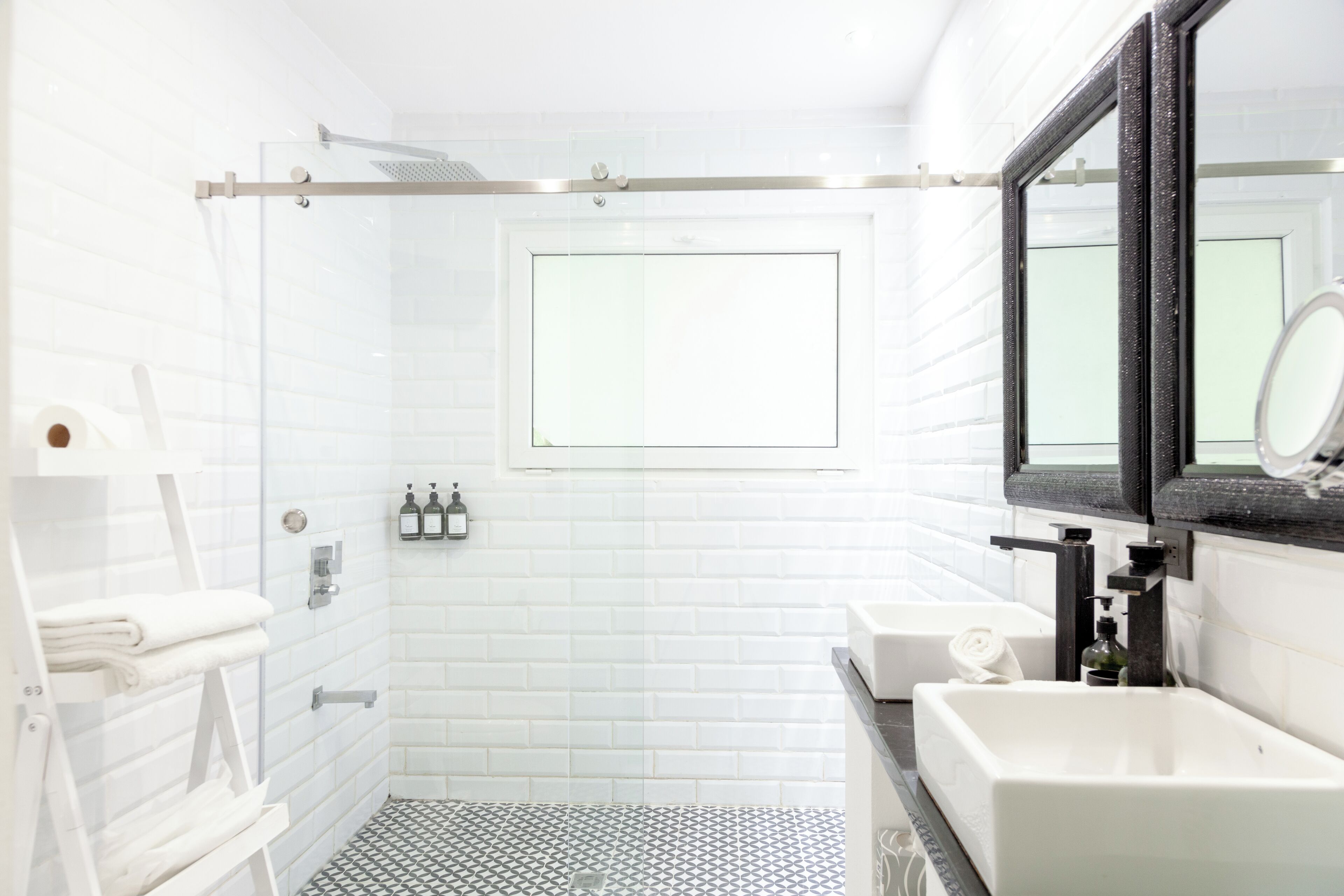 A modern bathroom with a shower, a large mirror, and a sink.