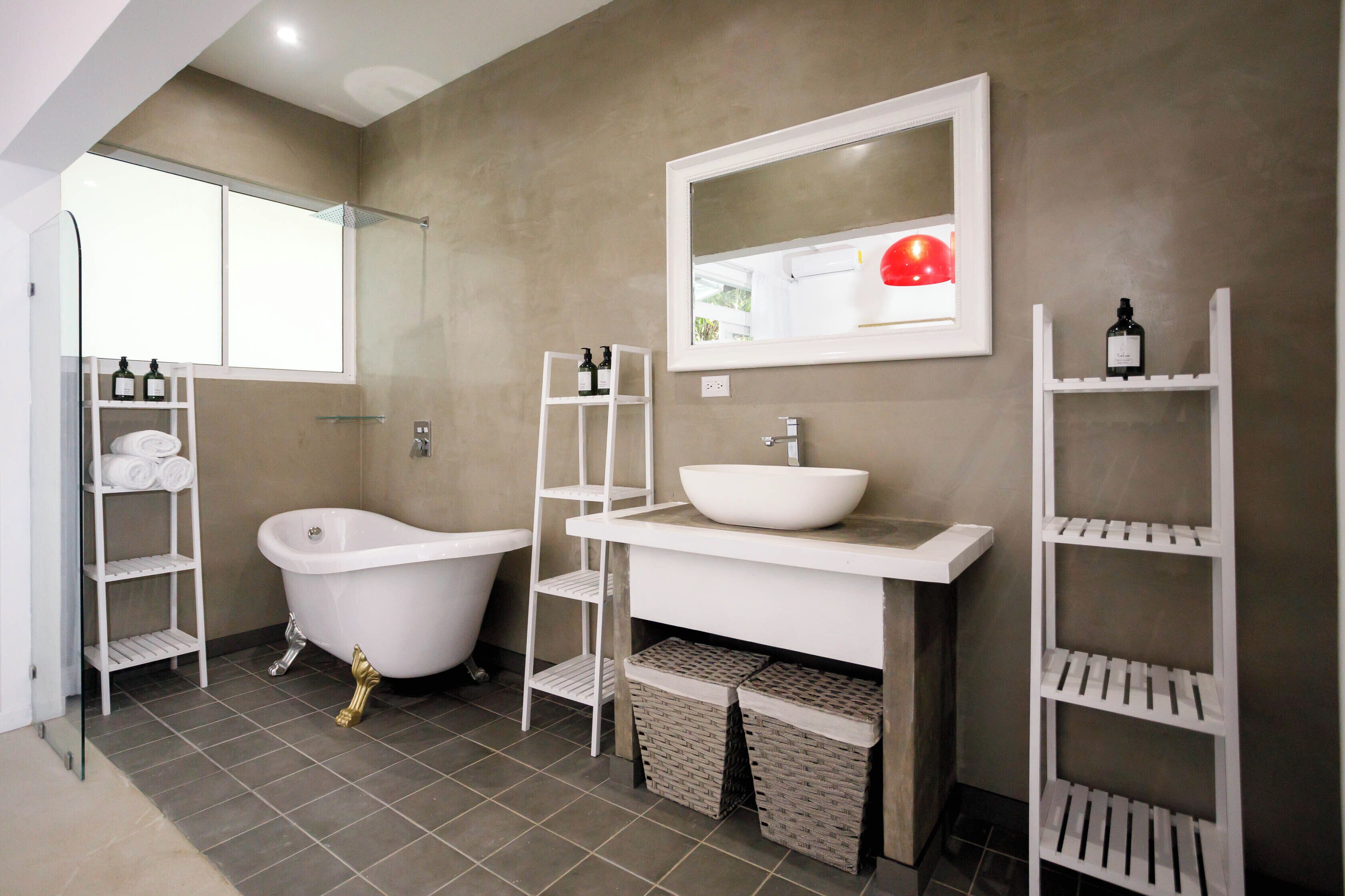 A modern bathroom with a freestanding bathtub, a large mirror, and built-in shelves for toiletries.