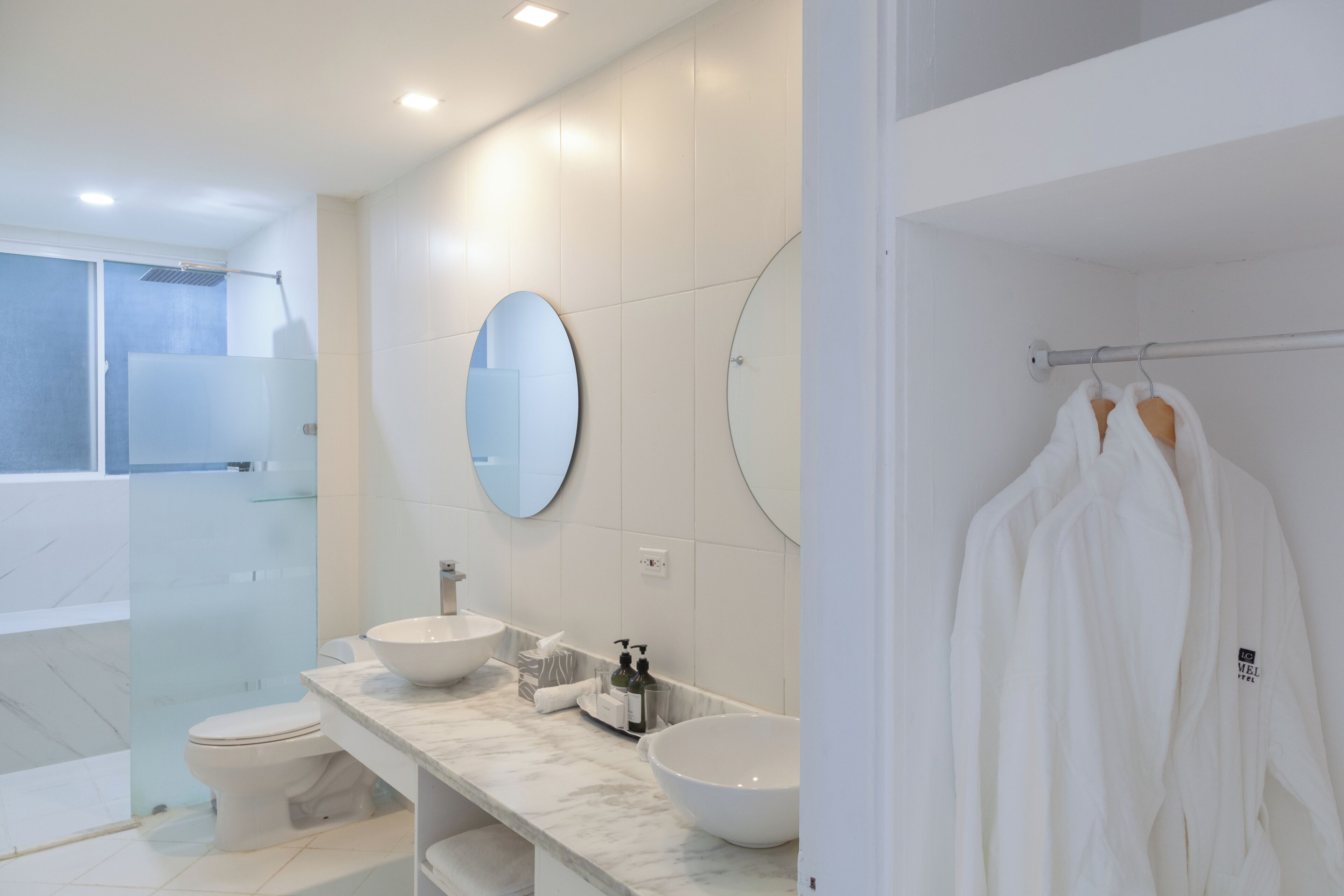 Une salle de bain moderne avec deux lavabos, un grand miroir et une douche à l’italienne.
