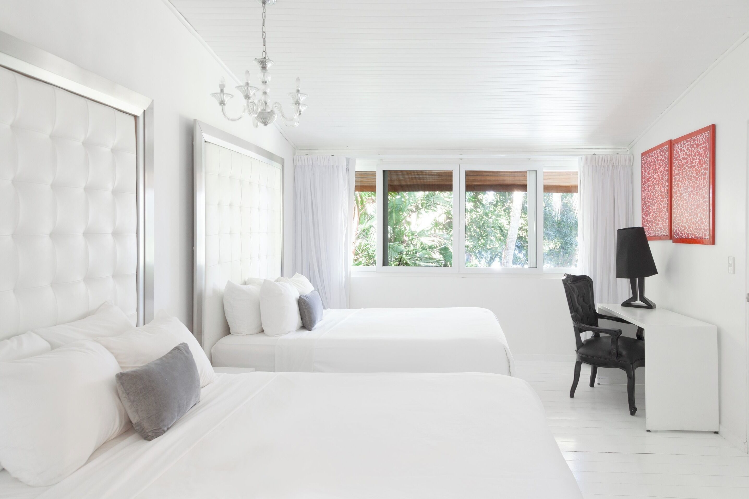 A modern hotel room with two beds, a desk, and a chair.