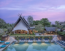 Un resort con piscina, sillas de descanso y un edificio de diseño arquitectónico singular.