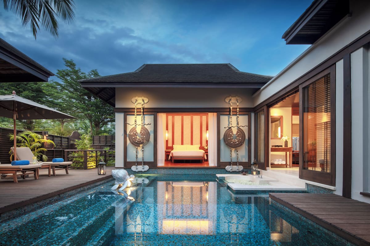 Ein moderner Poolbereich mit freiem Blick auf den Pool, Liegestühle und ein Schlafzimmer mit großem Fenster.