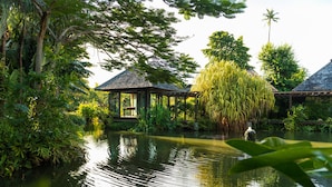 Ein friedlicher Garten mit Teich, hölzernen Bauten und üppigem Grün.