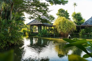 A tranquil garden with a pond, wooden structures, and lush greenery. - Anantara Mai Khao Phuket Villas (Mai Khao)
