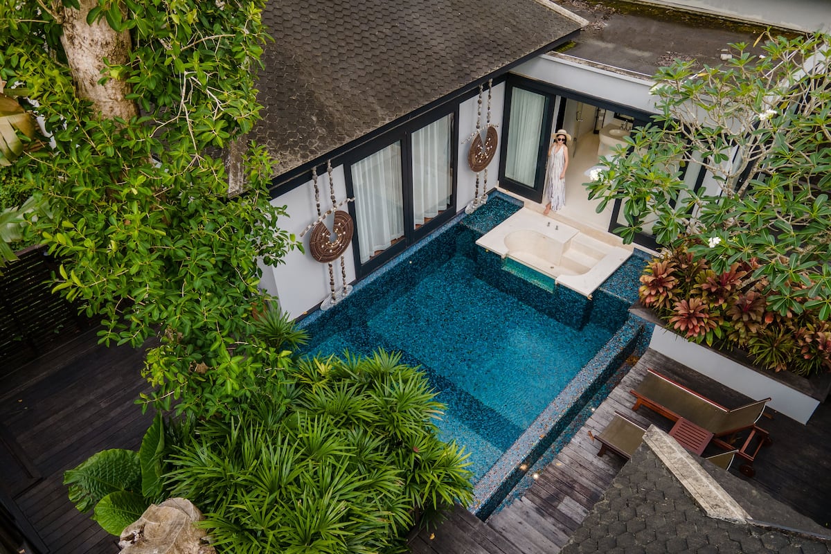 Ein Wohnhaus mit Swimmingpool, umgeben von üppiger Vegetation und einer Holzterrasse.