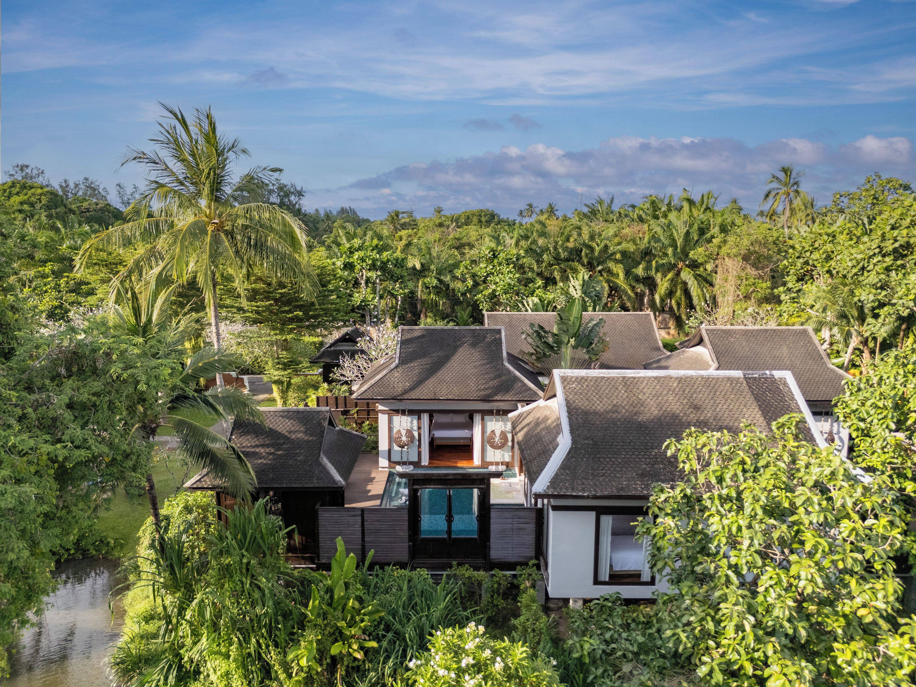Resort com vários edifícios cercado por vegetação exuberante e um corpo de água.