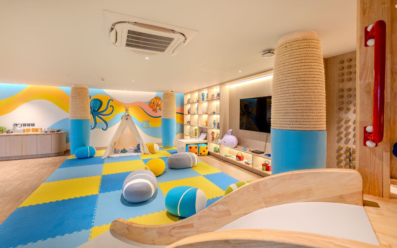 A children's play area with a colorful floor, play structures, and a shelf with toys.