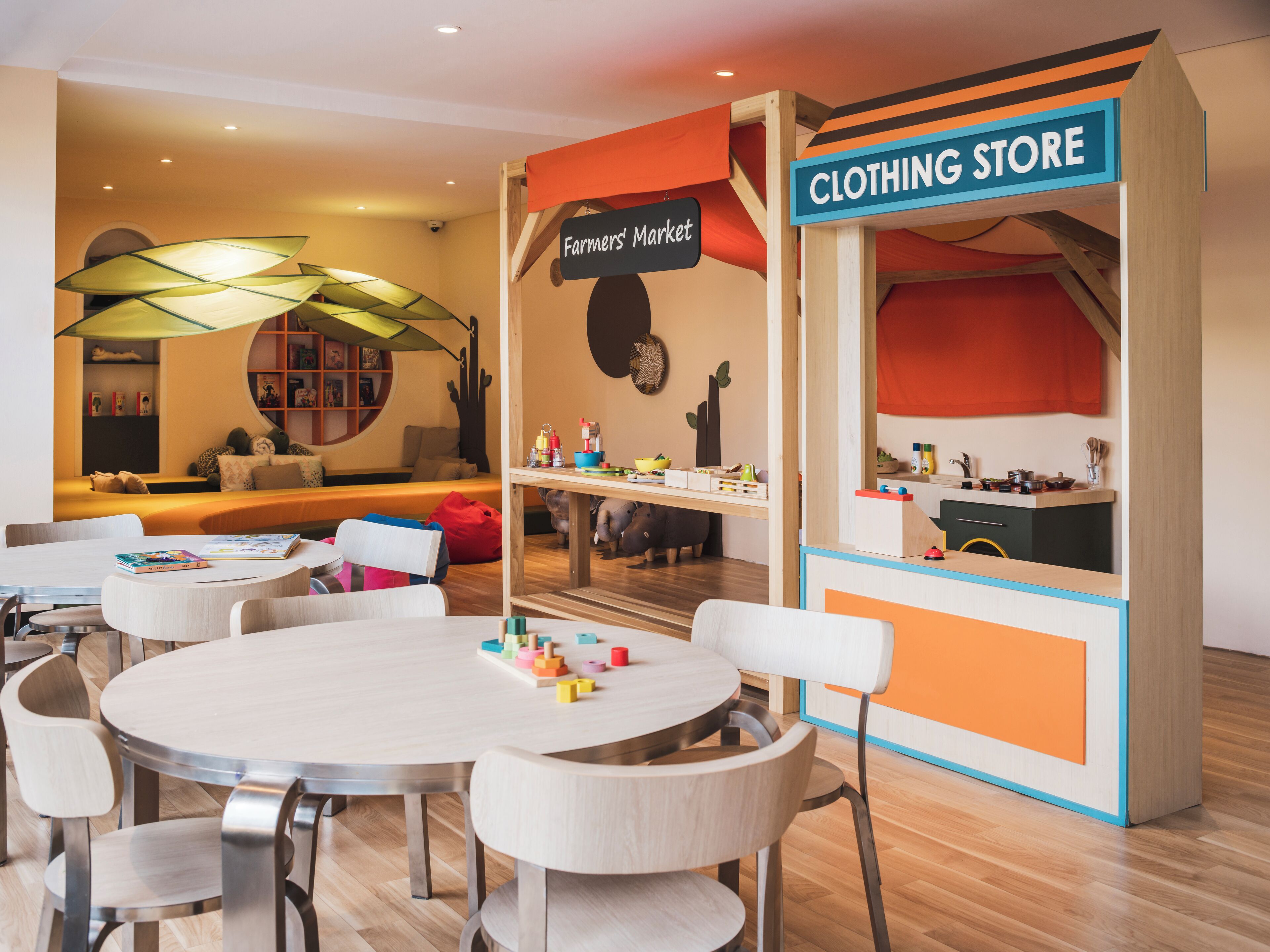 Ein Spielbereich für Kinder mit Tischen, Stühlen und einem Bekleidungsgeschäft.