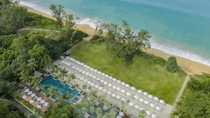 Vue aérienne d’un complexe hôtelier doté d’une piscine, d’une plage et de chaises longues.