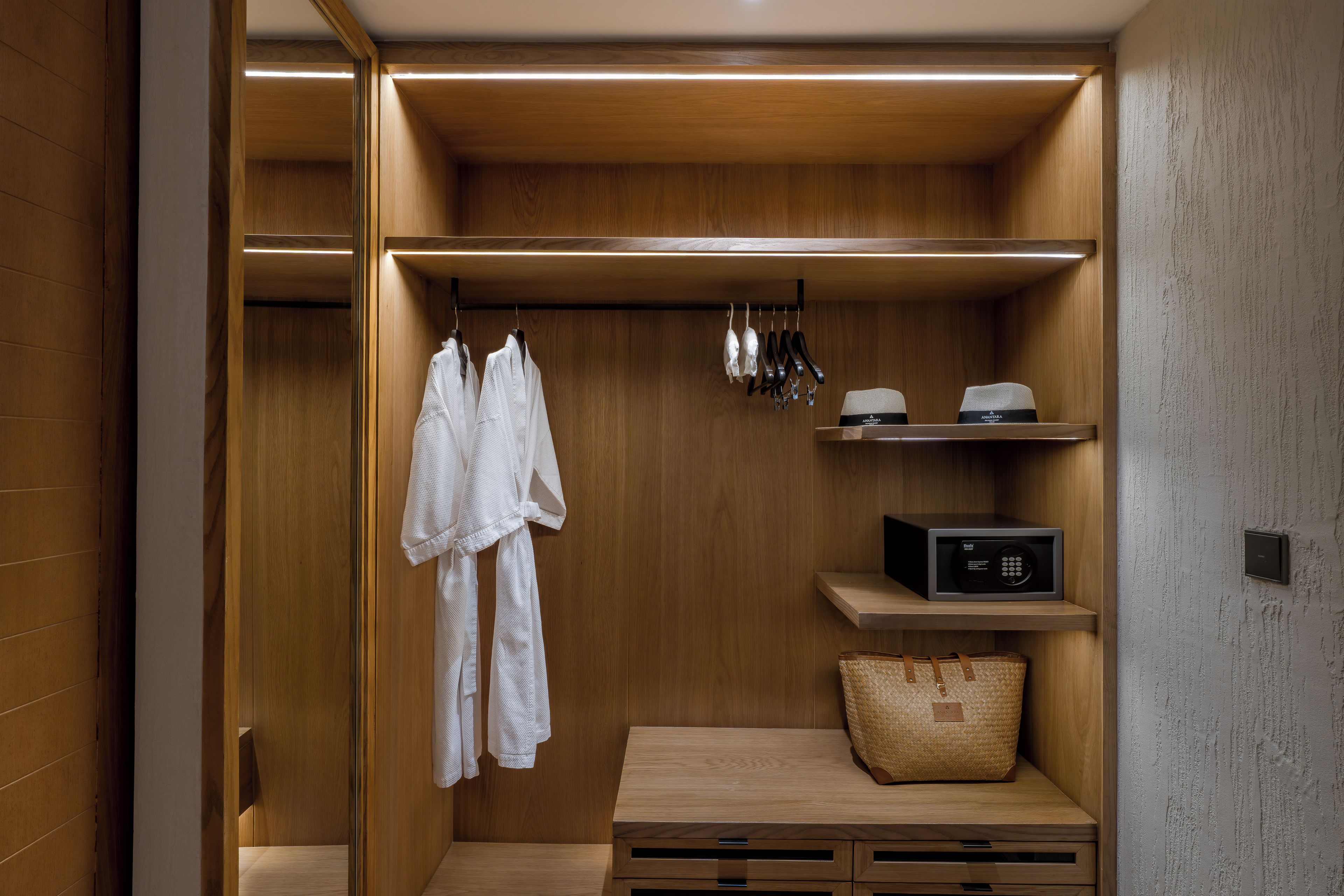 A walk-in closet with wooden shelving, a robe rack, a shoe rack, and a small wooden table with drawers.