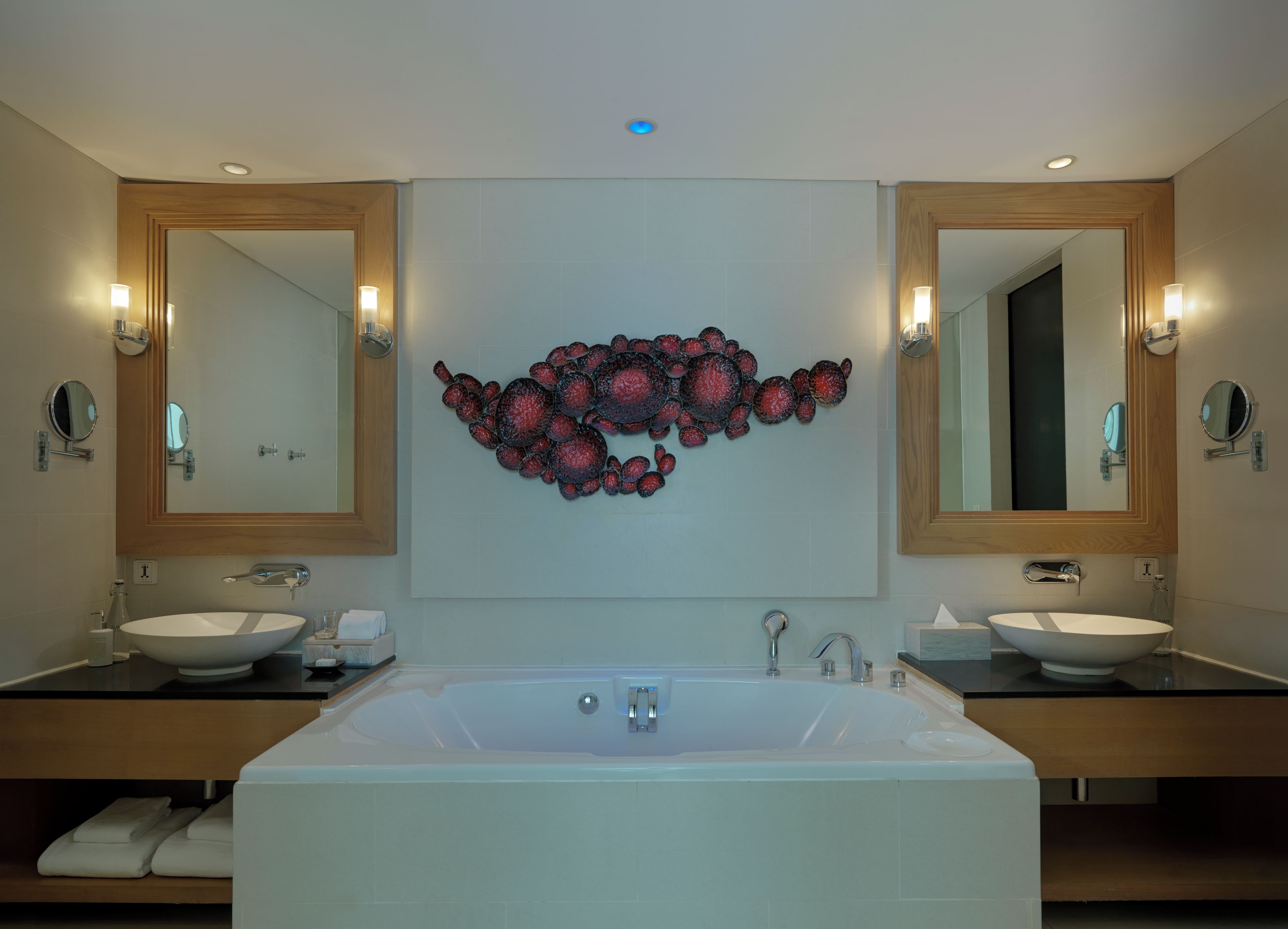 A modern bathroom with a large freestanding bathtub, two sinks, and wall-mounted mirrors.