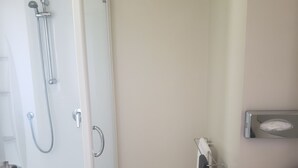 Un baño con ducha acristalada, lavamanos y perchero para toallas.