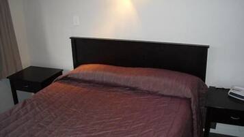 Quarto de hotel com cama, mesa de cabeceira e criado-mudo.