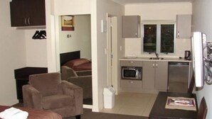 Un espacio habitable compacto con kitchenette, comedor y dormitorio.