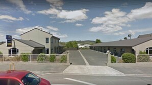 Un motel con aparcamiento y un edificio de techo plano.