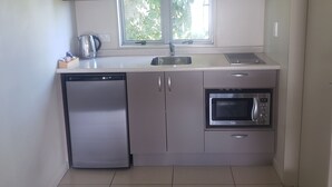 Una cocina compacta con lavavajillas, microondas y una ventana sobre el fregadero.