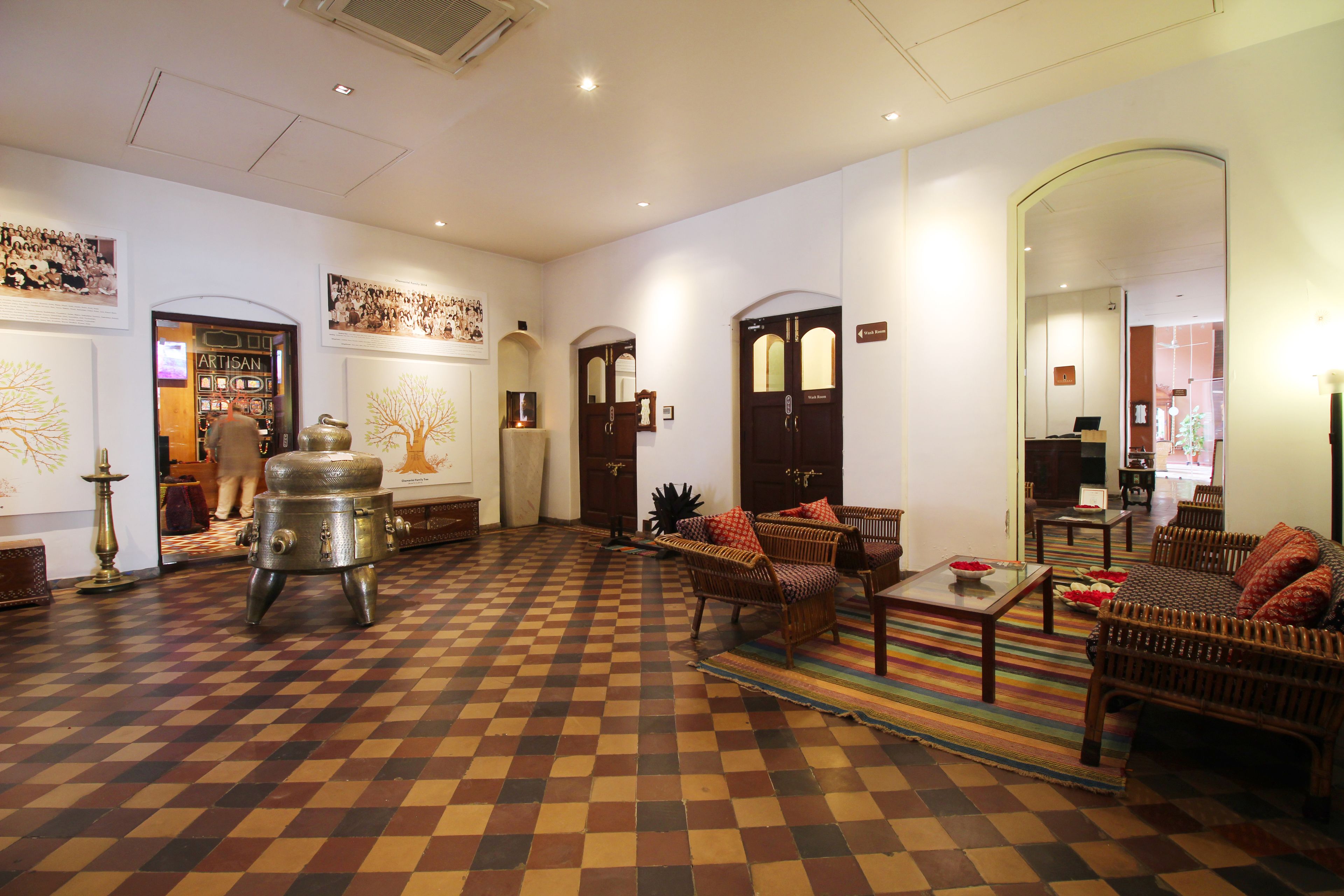 A checkered floor, wicker furniture, and a large metal stove in a room with white walls and wooden doors.
