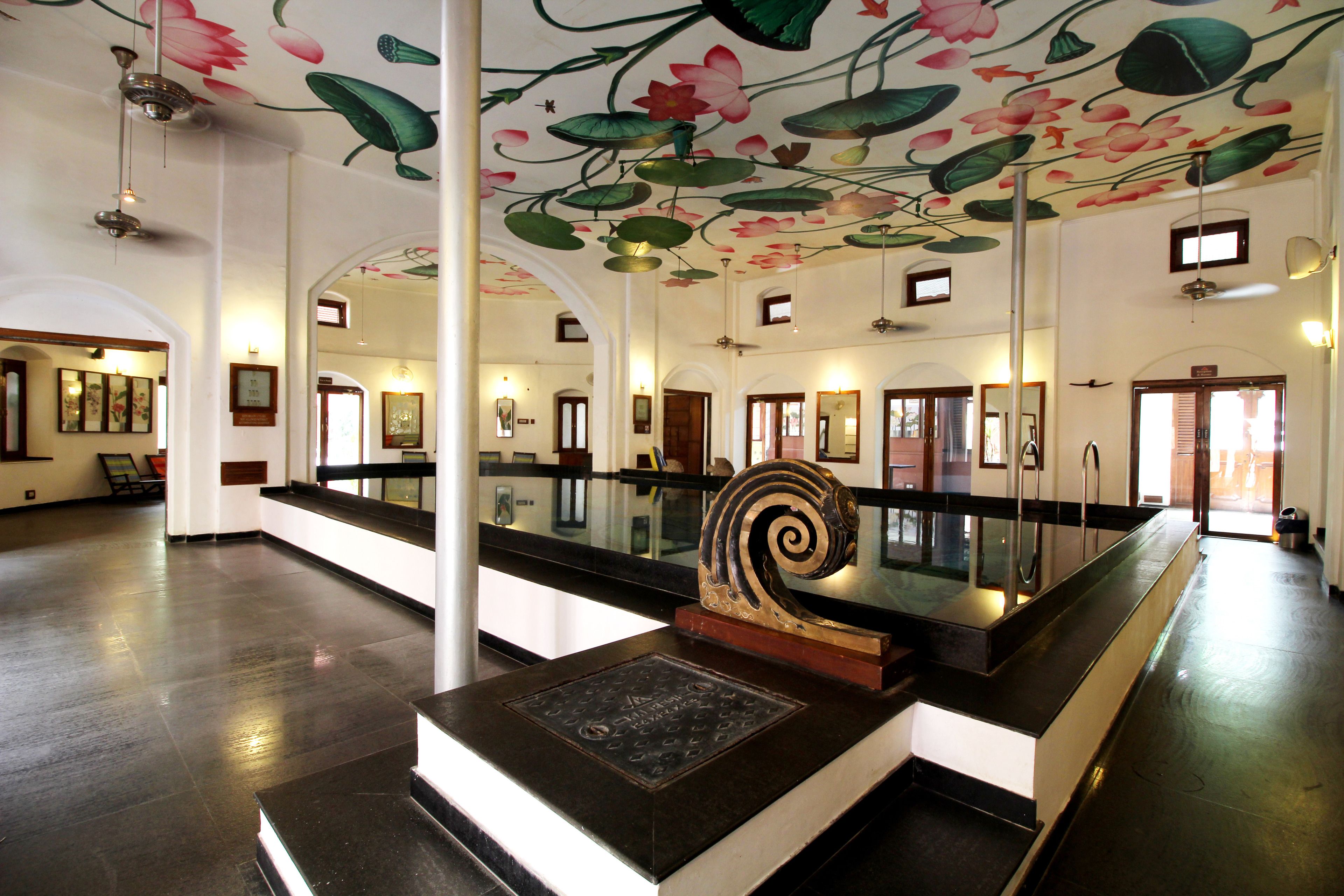 Un vestíbulo amplio con una decoración central, una pared espejada y un techo decorado con motivos florales.