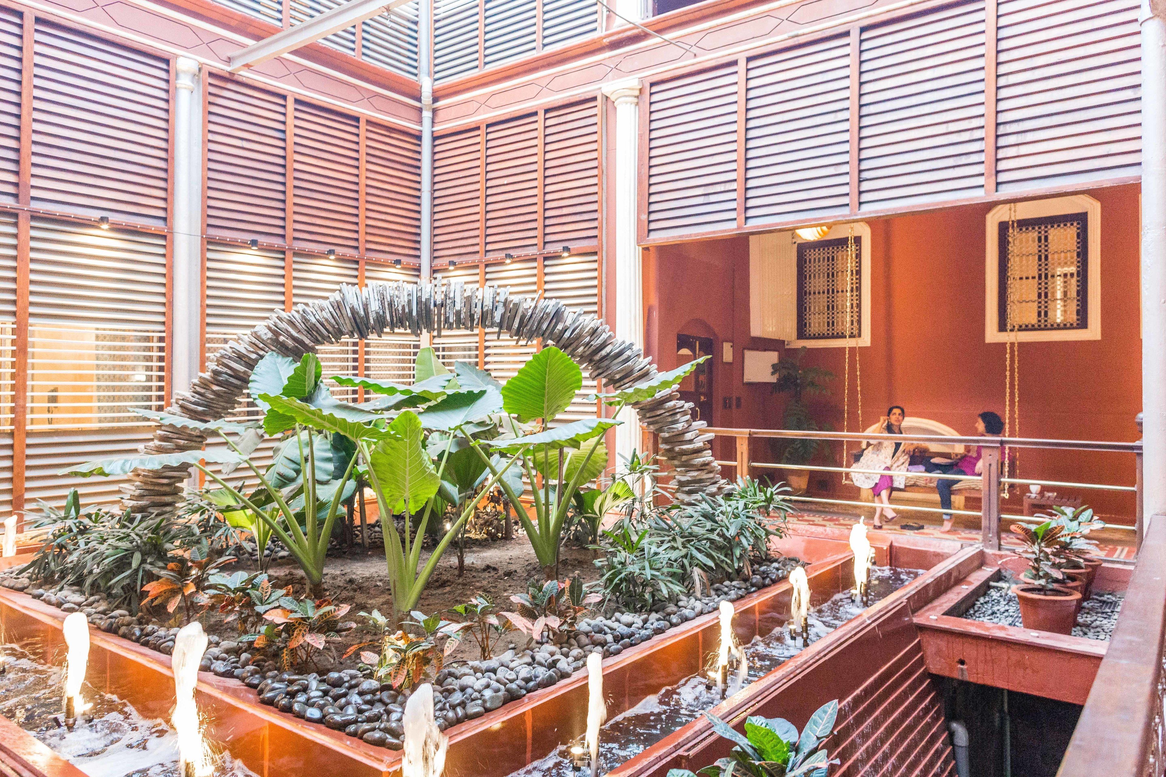 A modern atrium with a central garden, wooden slatted walls, and potted plants.