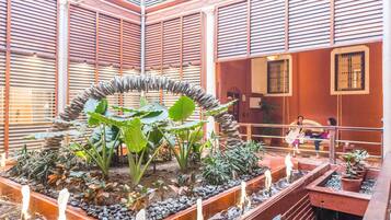 A modern atrium with a central garden, wooden slatted walls, and potted plants.