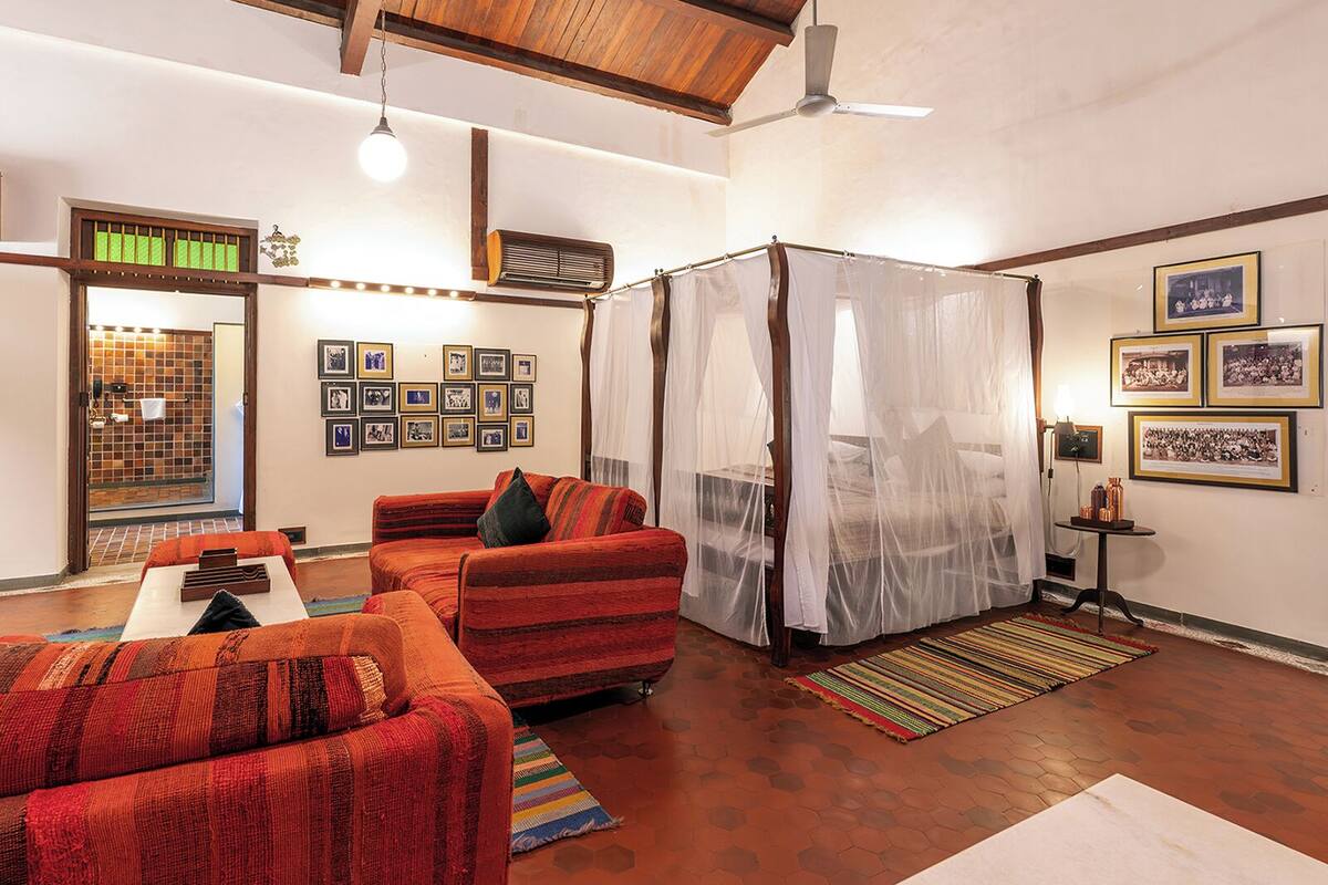 A spacious living room with a high ceiling, a large bed with a canopy, and a seating area with sofas.