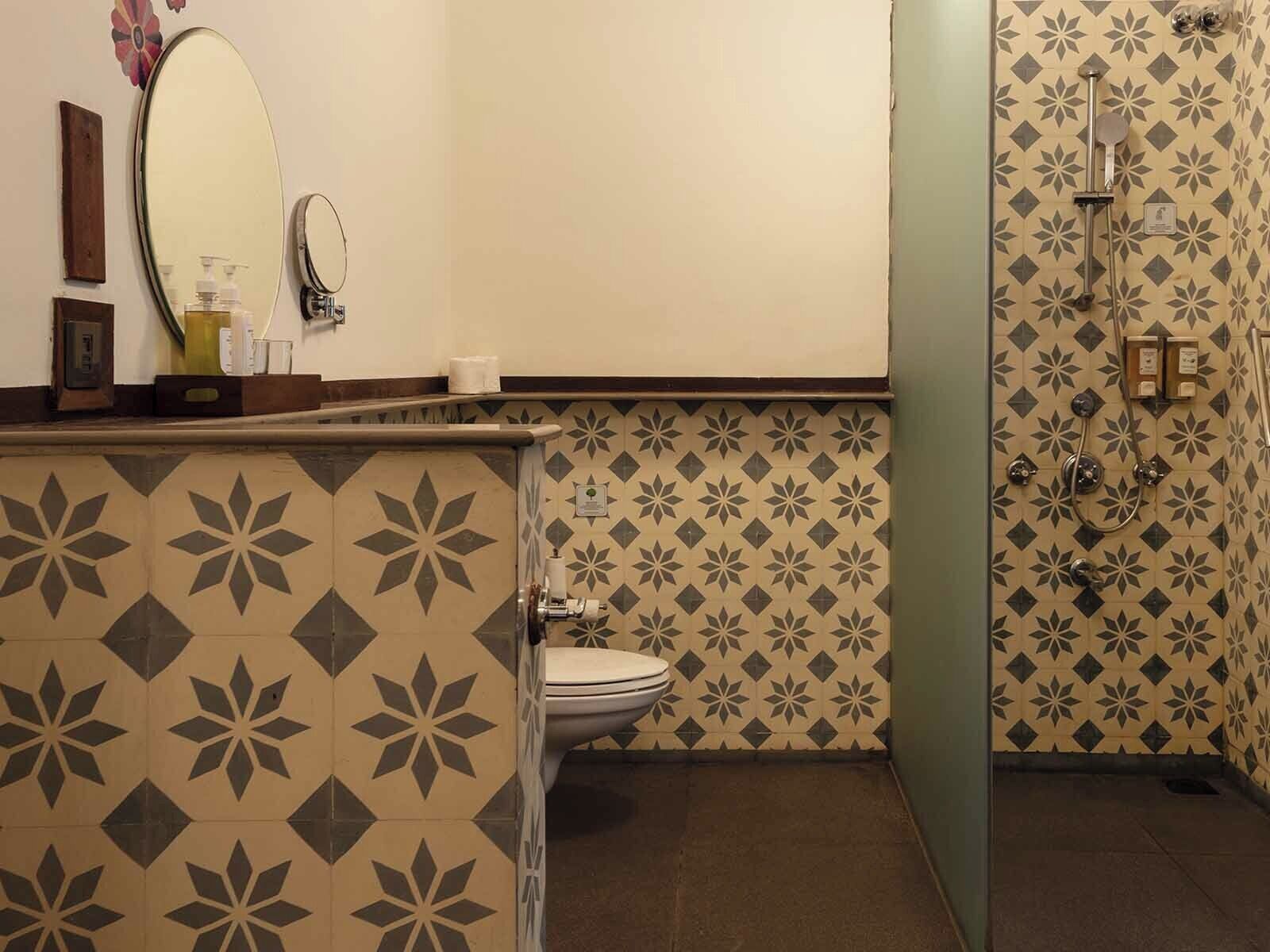 A bathroom with a toilet, a sink with a mirror, and a shower area with a showerhead and control panel.