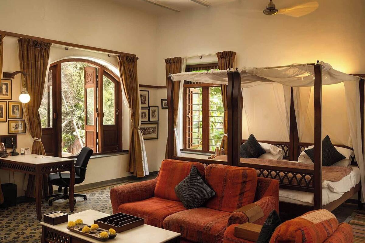 A room with a four-poster bed, a sofa, a desk, and a chair.