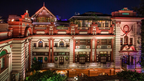 A multi-story building with a traditional architectural style, featuring balconies, columns, and a central courtyard.