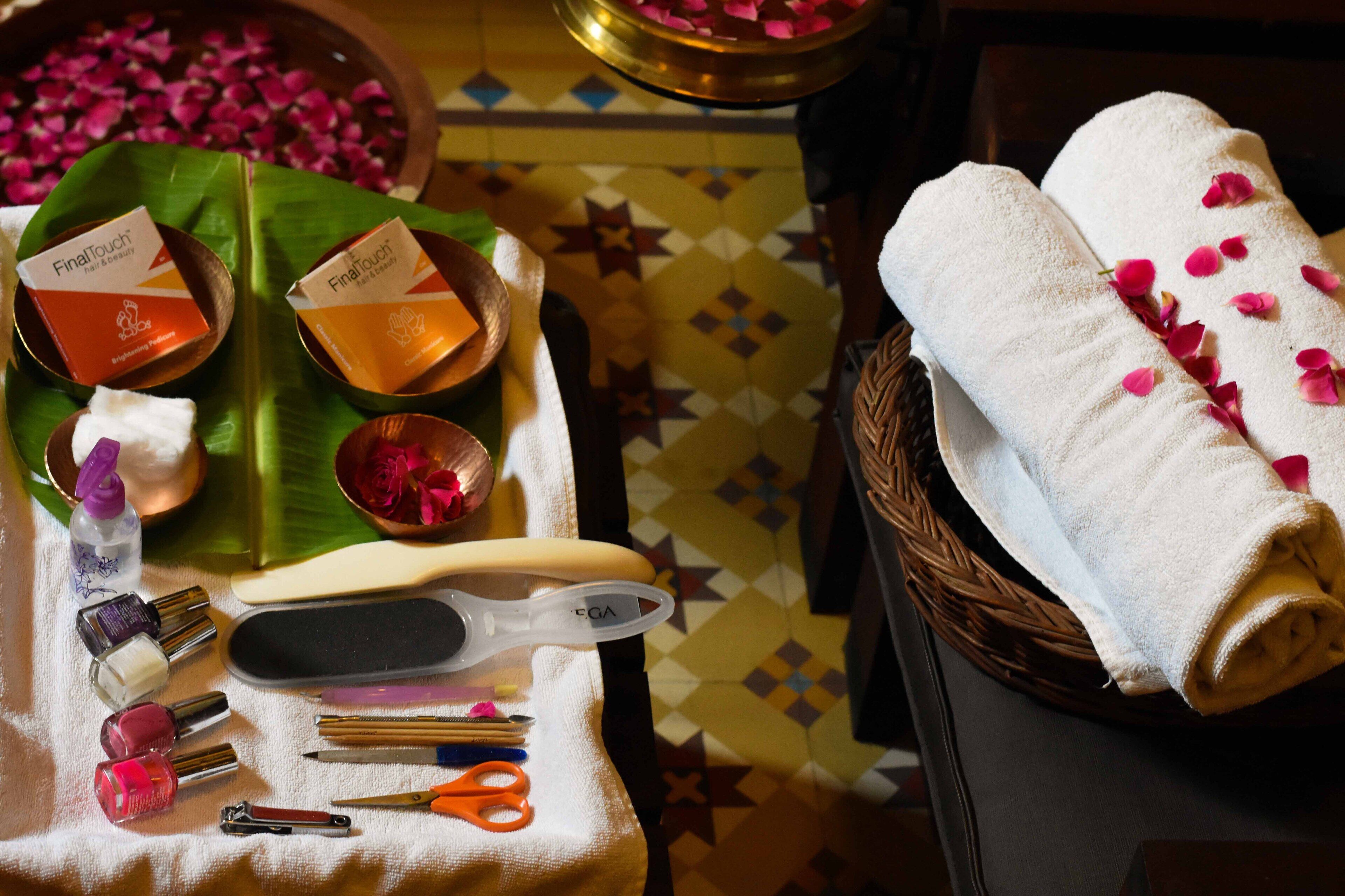 A bathroom vanity with toiletries, a towel, and a decorative bowl of pink petals.