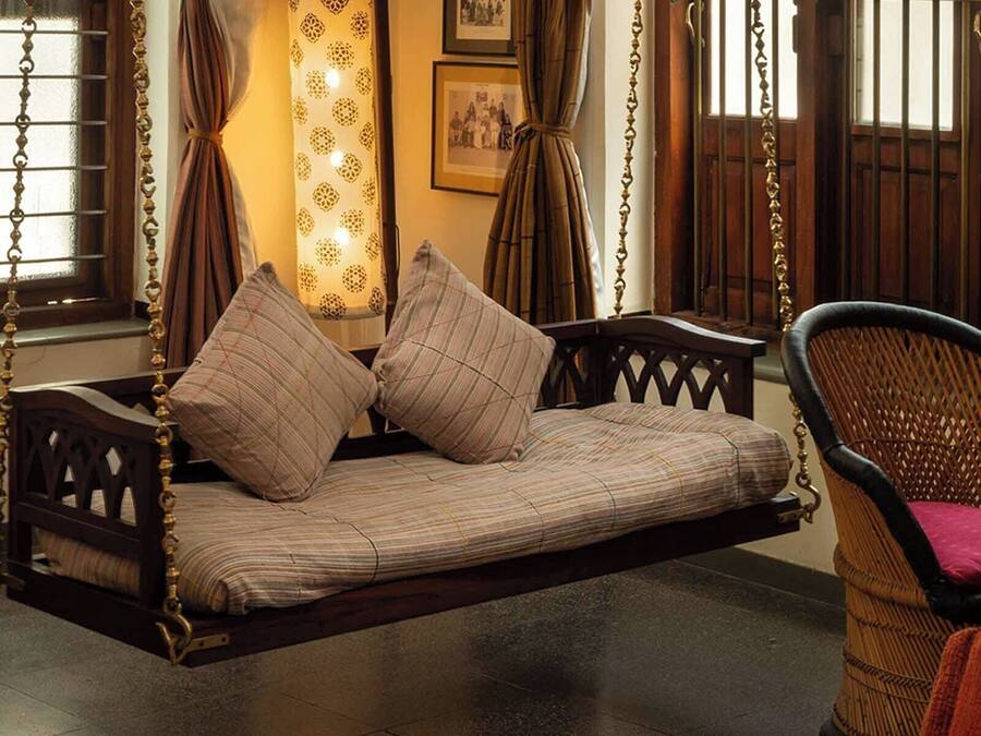 A traditional room with a wooden swing bed, a wicker chair, and a patterned curtain.