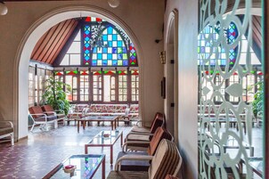 A spacious lobby with a high arched ceiling, a large stained glass window, and a seating area with sofas and armchairs.